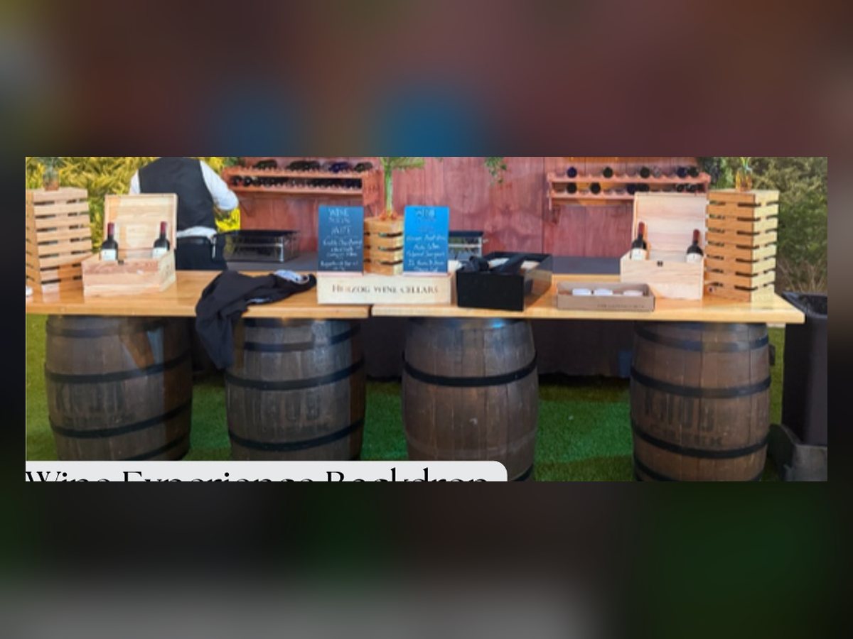 Wine experience backdrop with barrel bar and greenery